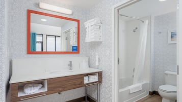 A modern bathroom with a white sink, mirror, and shower.
