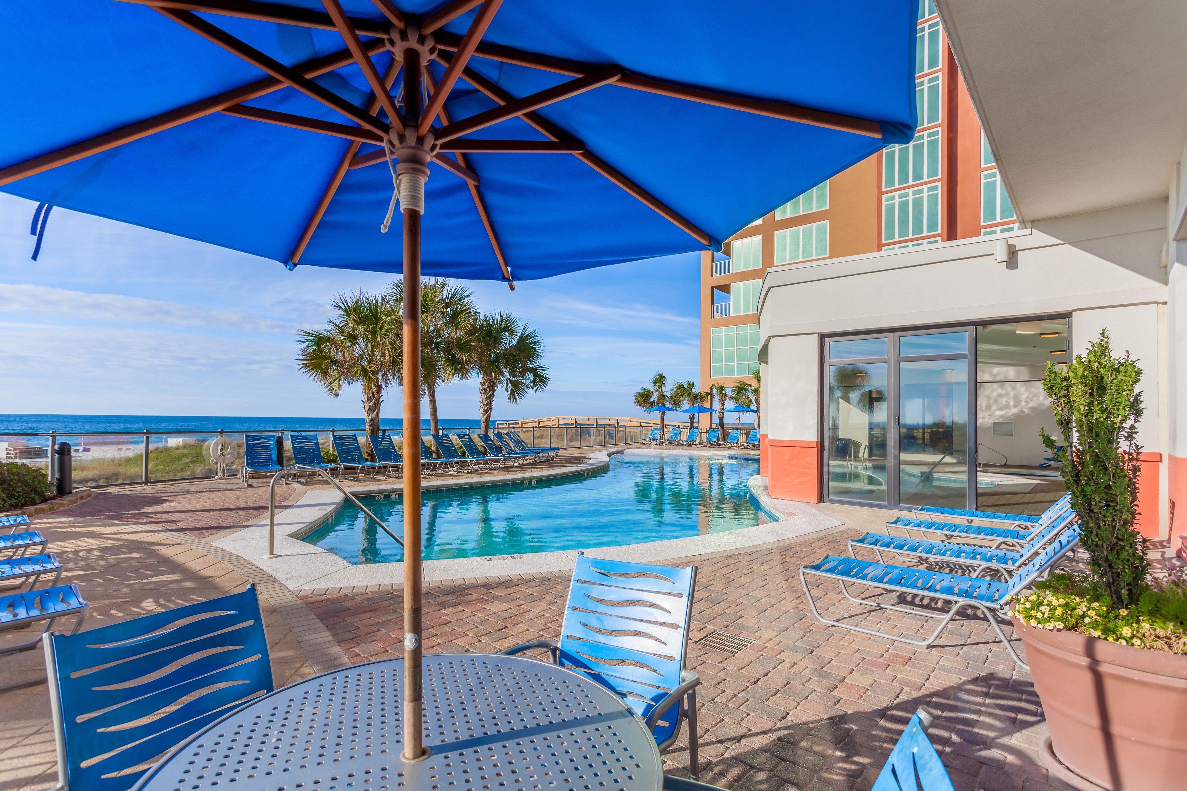 A poolside area with lounge chairs, a table, and a large umbrella.