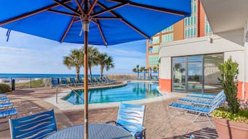 A poolside area with lounge chairs, a table, and a large umbrella.