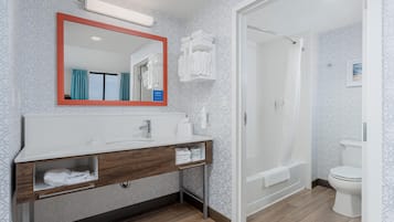 A modern bathroom with a large mirror, white sink, and shower.