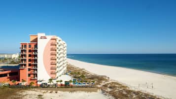 A beachfront hotel with multiple floors, a pool, and a beach area.