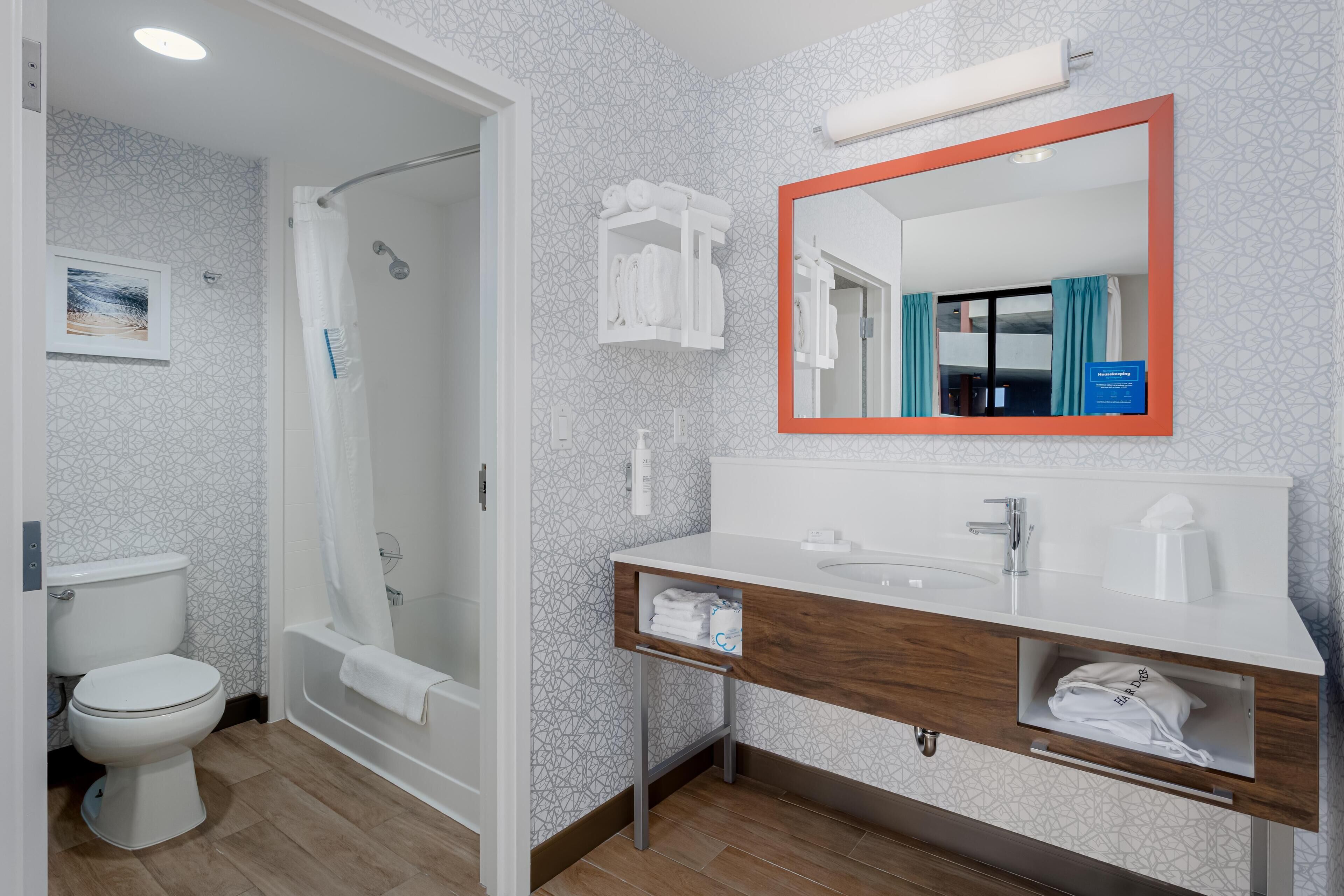 Een moderne badkamer met douche, toilet en wastafel met spiegel.