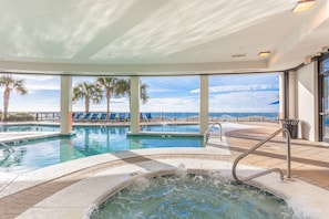 Un área de piscina con un jacuzzi, sillones de descanso y vista al océano.