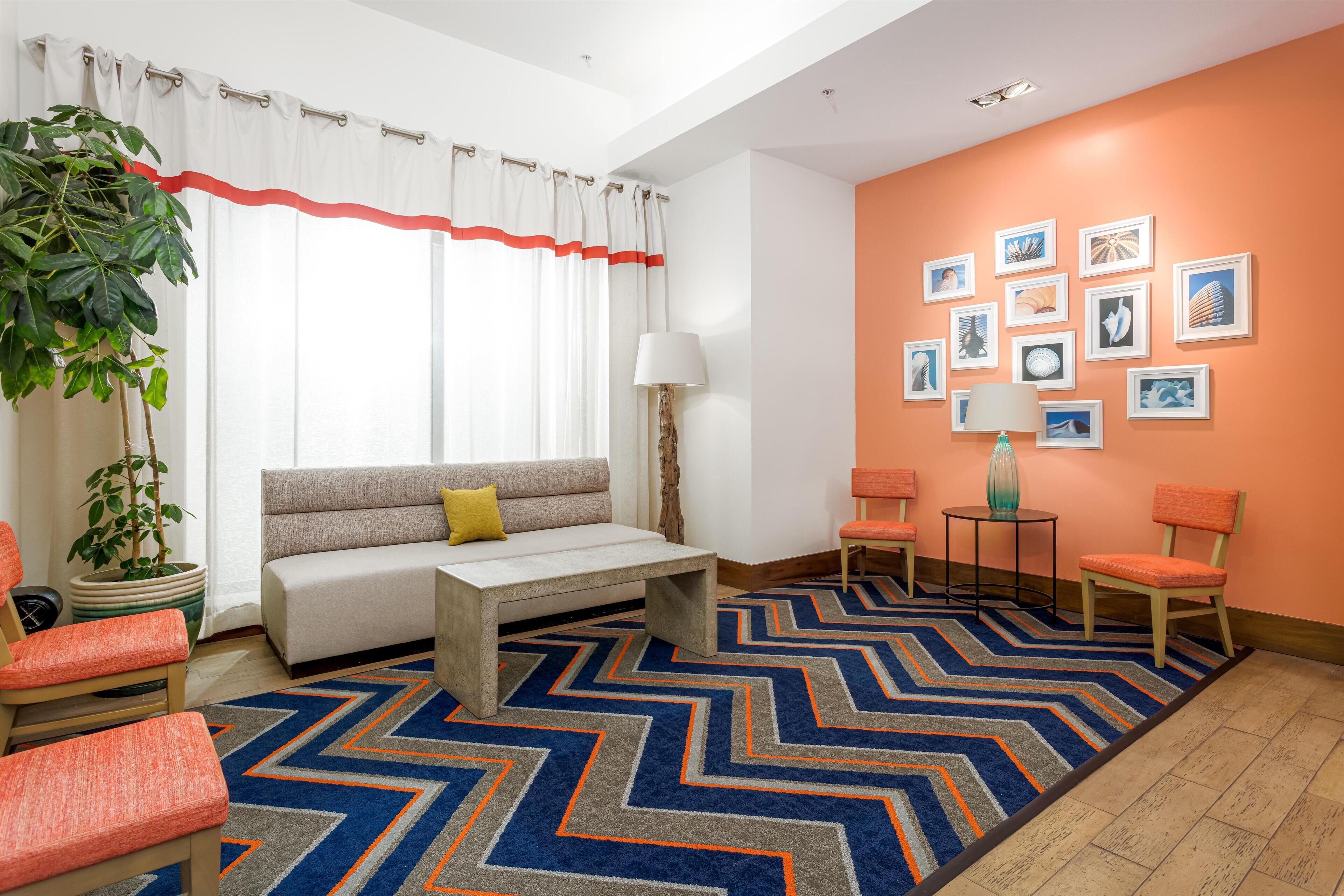 Un salon moderne avec un canapé, des fauteuils, une table basse et un tapis à motifs.