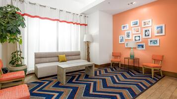 Un salon moderne avec un canapé, des fauteuils, une table basse et un tapis à motifs.