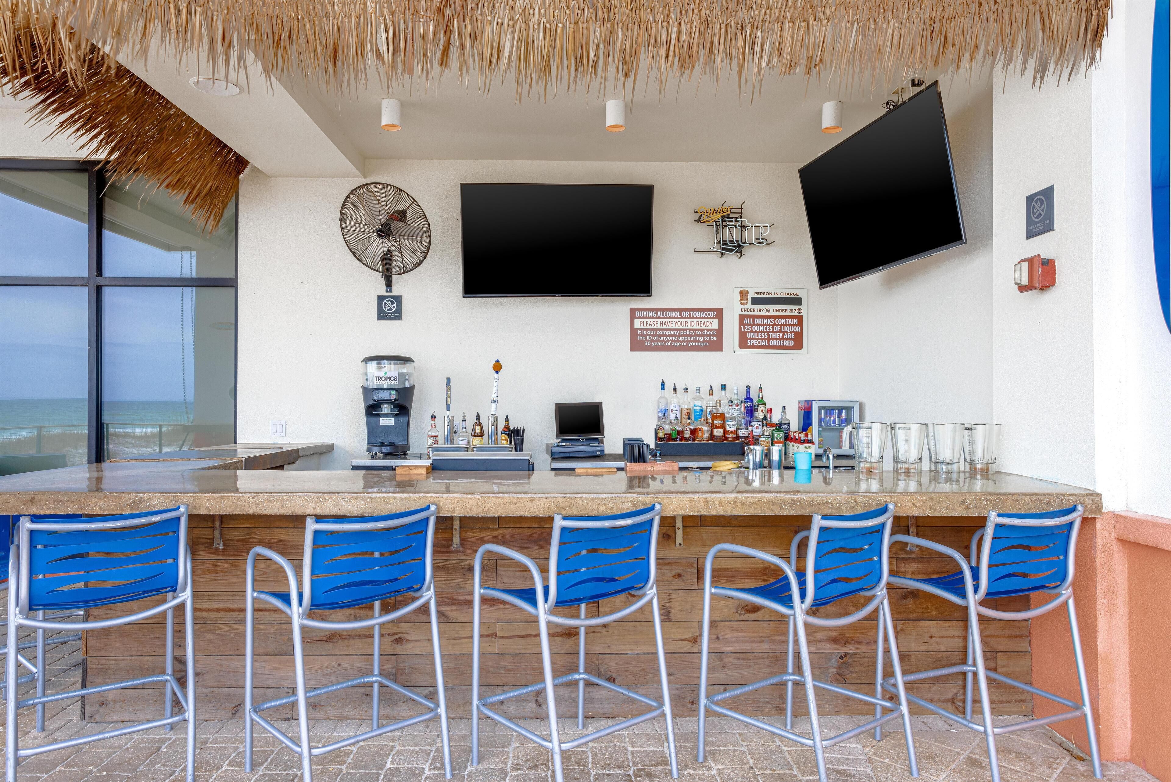 A bar area with a flat-screen TV, a fan, and a sign about alcohol and tobacco.