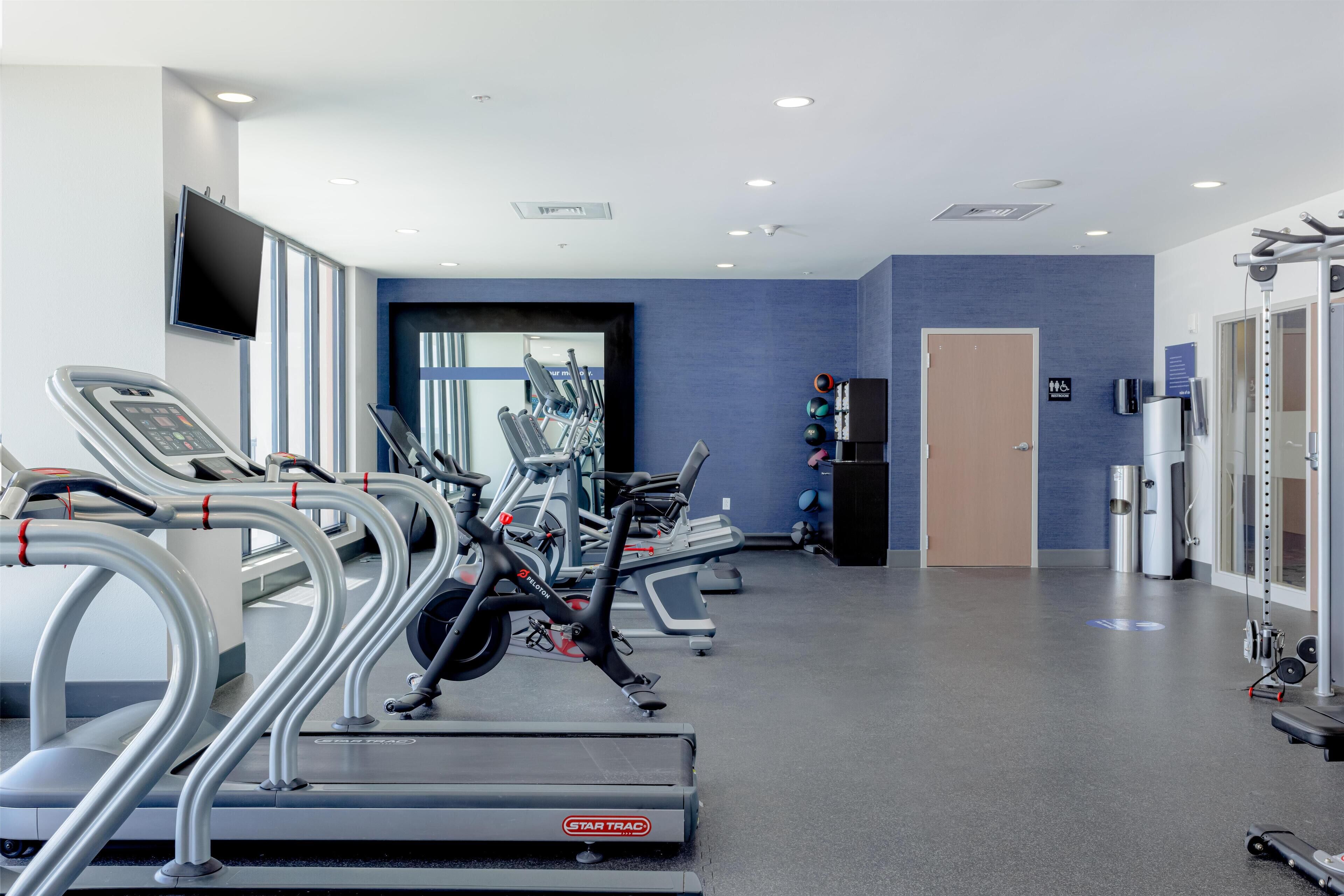 A gym with treadmills, elliptical machines, and weight equipment.