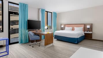 Une chambre d’hôtel équipée d’un lit, d’un bureau, d’une chaise, d’une télévision et offrant une vue sur le balcon.