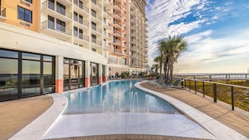 Un hotel con piscina, vista al mar y una palmera.