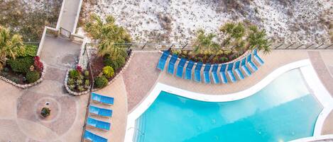 Luchtbeeld van een resort met een zwembad, ligbedden en palmbomen.