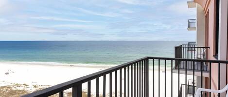 A balcony with a view of the beach and ocean.