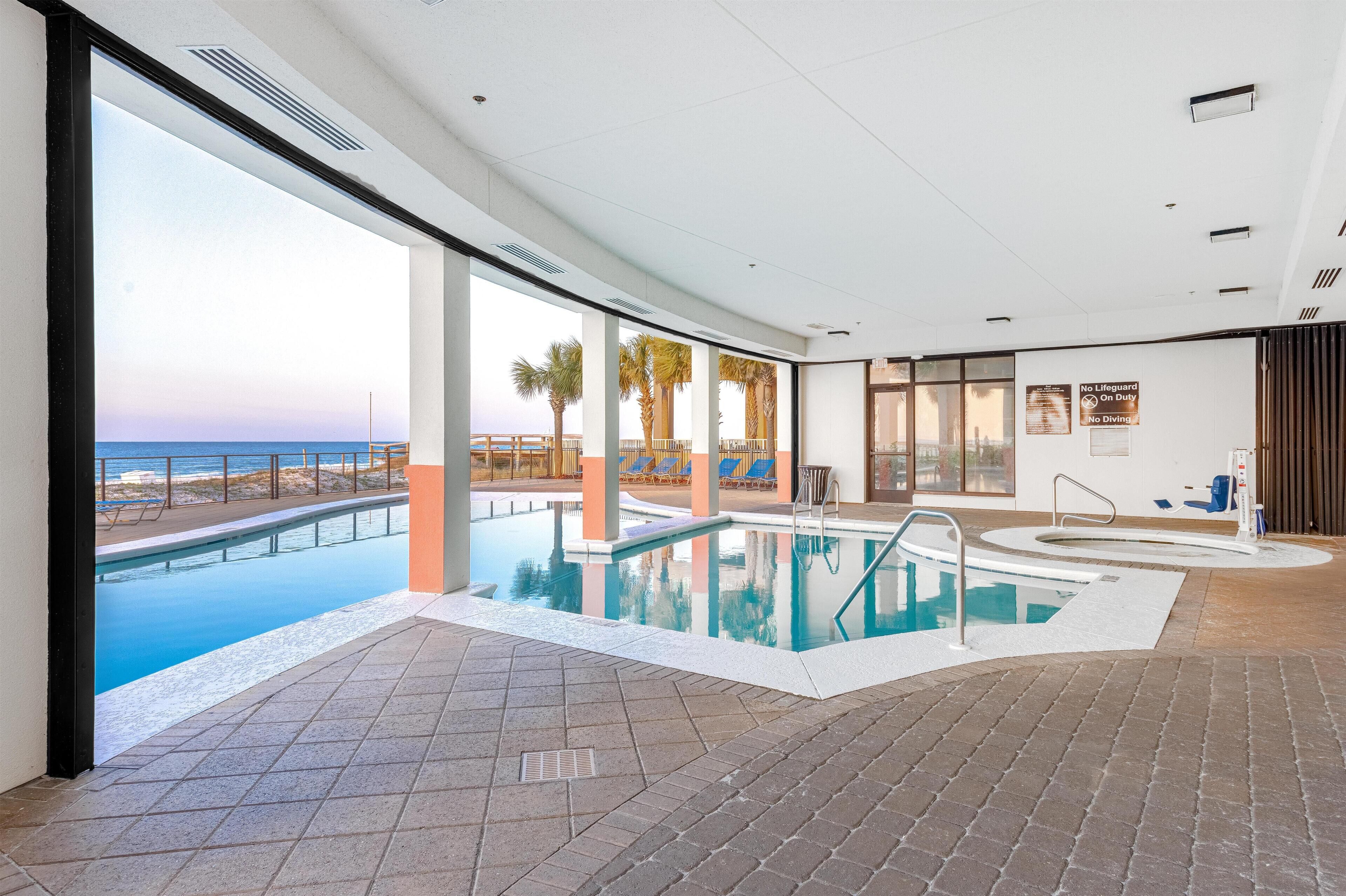 Une piscine intérieure avec vue sur la plage et les palmiers.