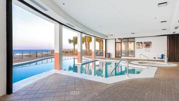 Une piscine intérieure avec vue sur la plage et les palmiers.