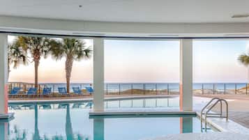Una piscina techada, una piscina al aire libre, sombrillas