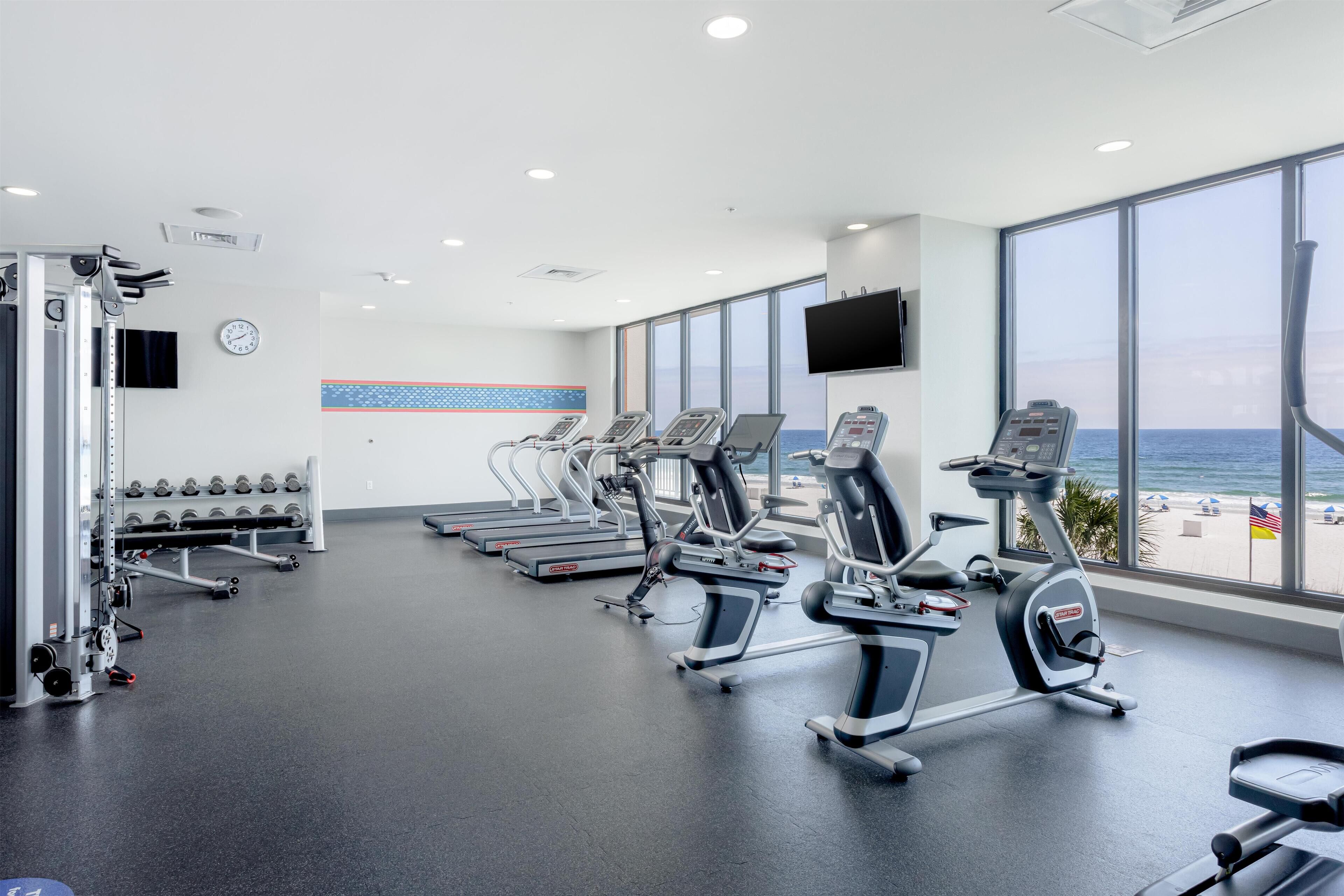 Une salle de sport équipée de machines de cardio, de machines de musculation et d’haltères.