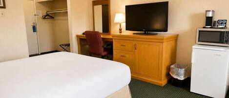 A hotel room with a bed, a desk with a chair, a television, a microwave, and a small refrigerator.