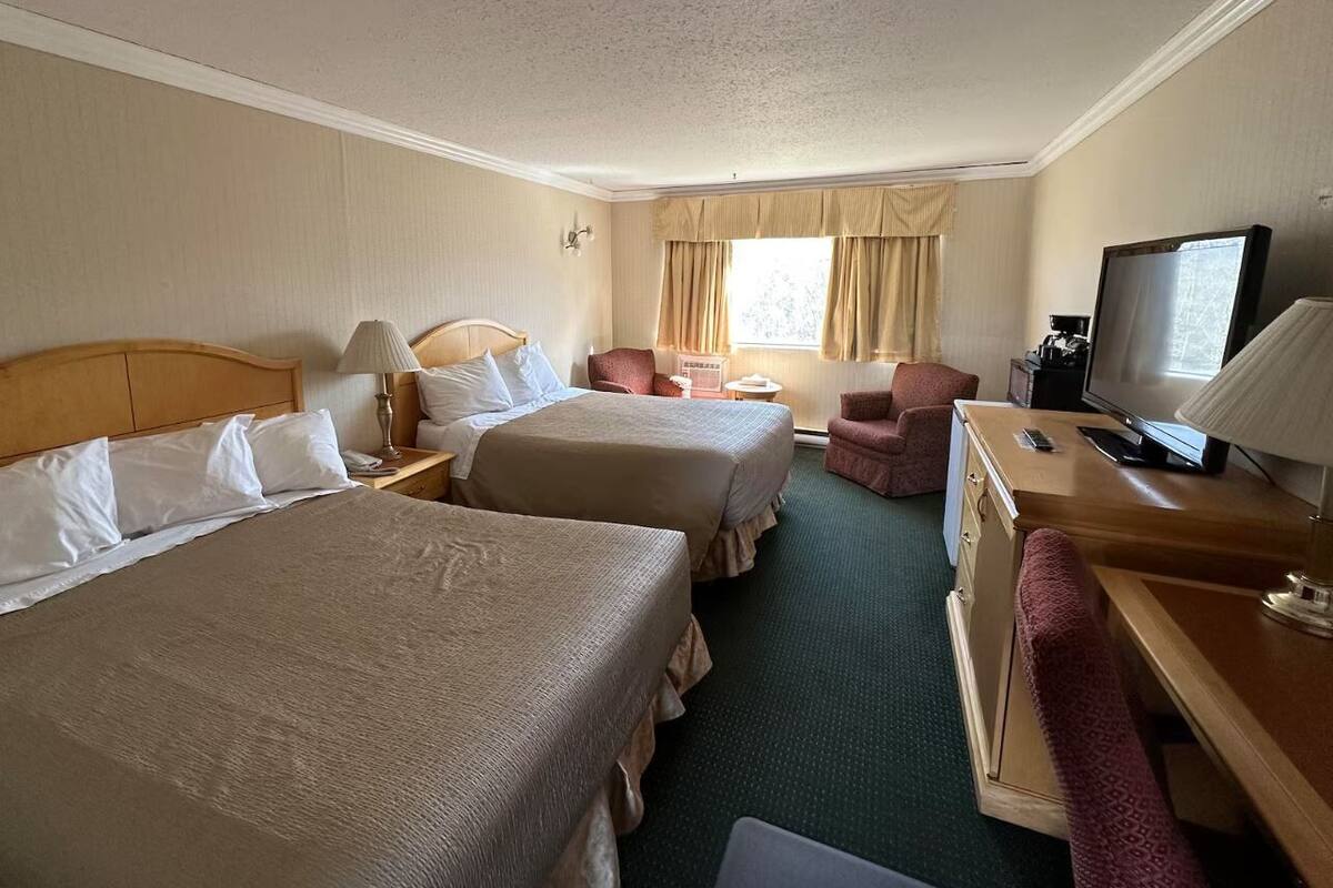 Habitación de hotel con dos camas, un escritorio, un televisor y una silla.