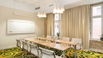 A conference room with a long table, chairs, a whiteboard, and a view of a brick building through large windows.