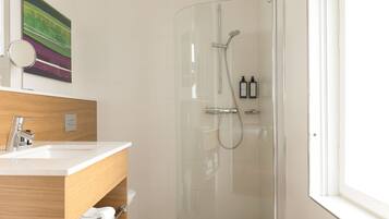 A modern bathroom with a glass-enclosed shower, a wooden vanity with a sink, and a mirror.