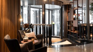 A lobby with a revolving door, a reception desk, and a seating area with a vase and a lamp. - Elite Hotel Esplanade (Malmö)