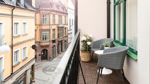 A balcony with wicker chairs and a table, overlooking a street with historic buildings. - Elite Hotel Esplanade (Malmö)