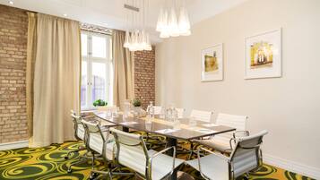 A conference room with a long table, white chairs, and hanging pendant lights.