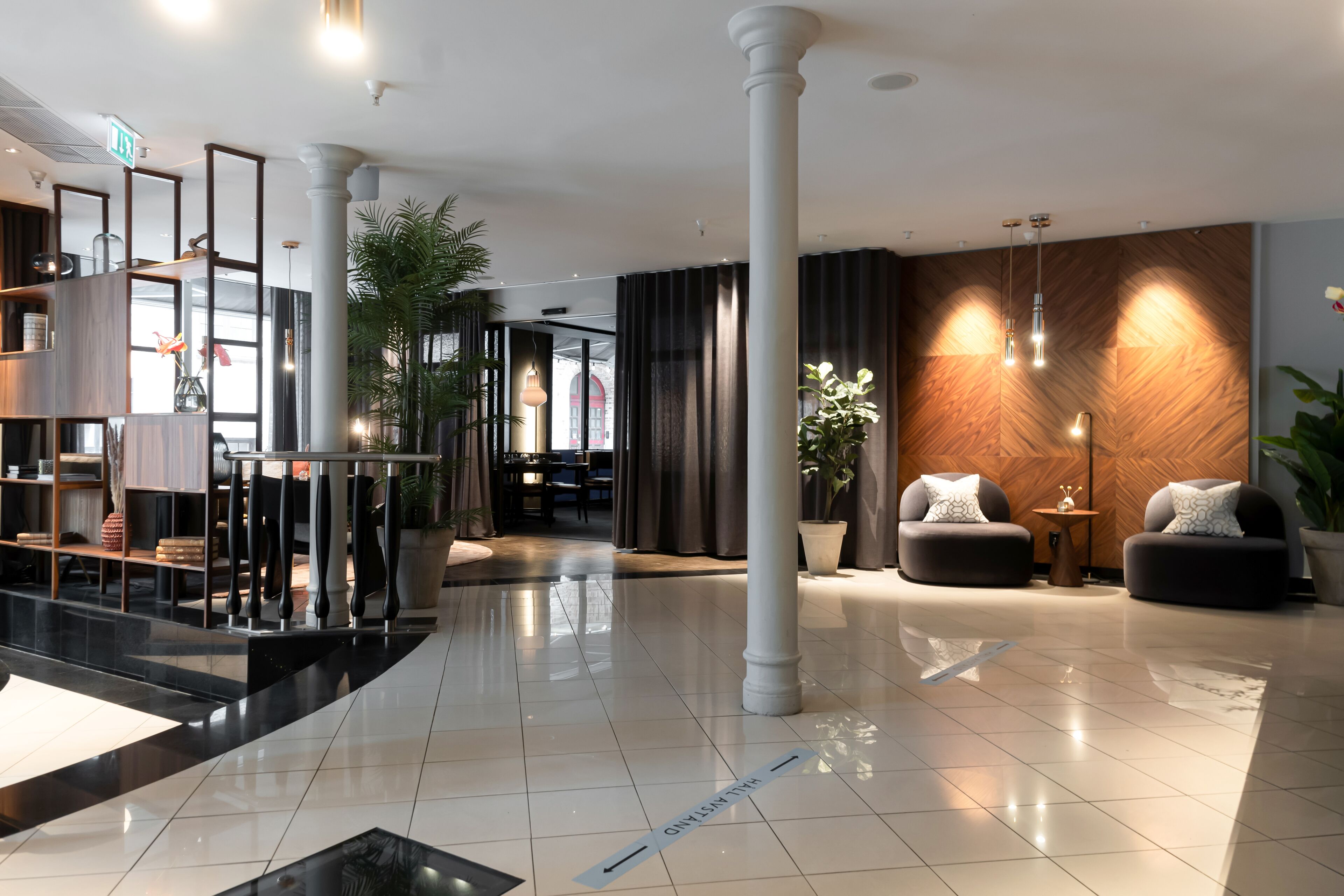 A modern lobby with a polished floor, a reception desk, seating area, and a large column.