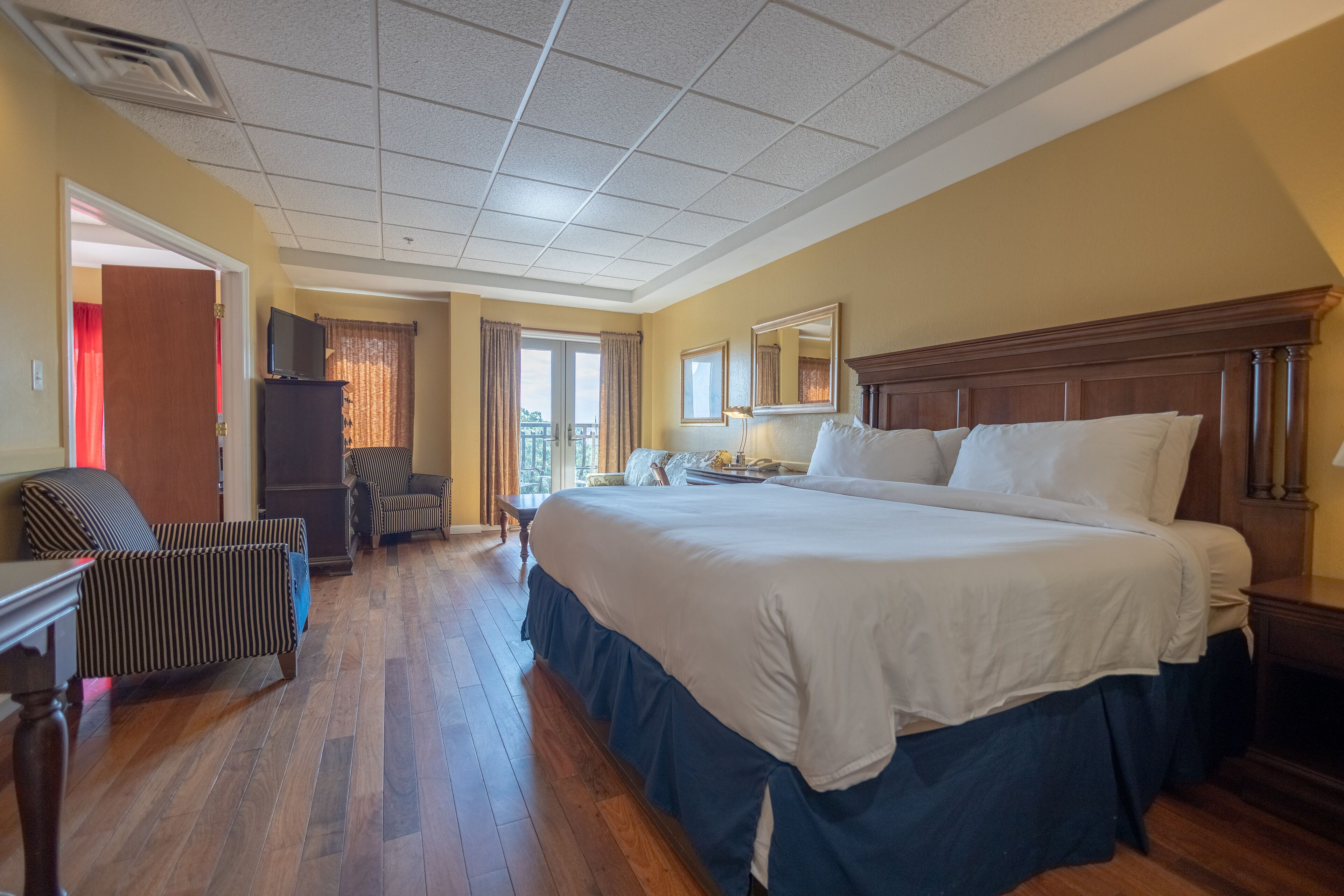 A hotel room with a large bed, a TV, a desk, and a chair.