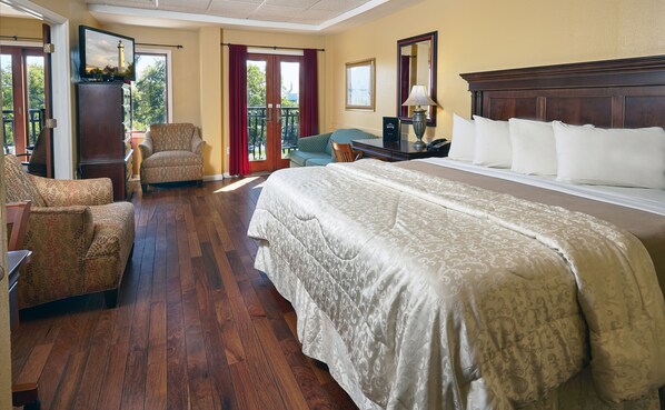 A hotel room with a large bed, a chair, a desk, and a view of the outdoors.