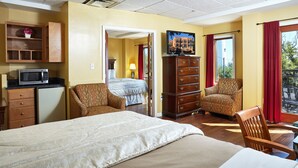 A hotel room with a bed, a dresser, a chair, a TV, and a view of the outdoors.