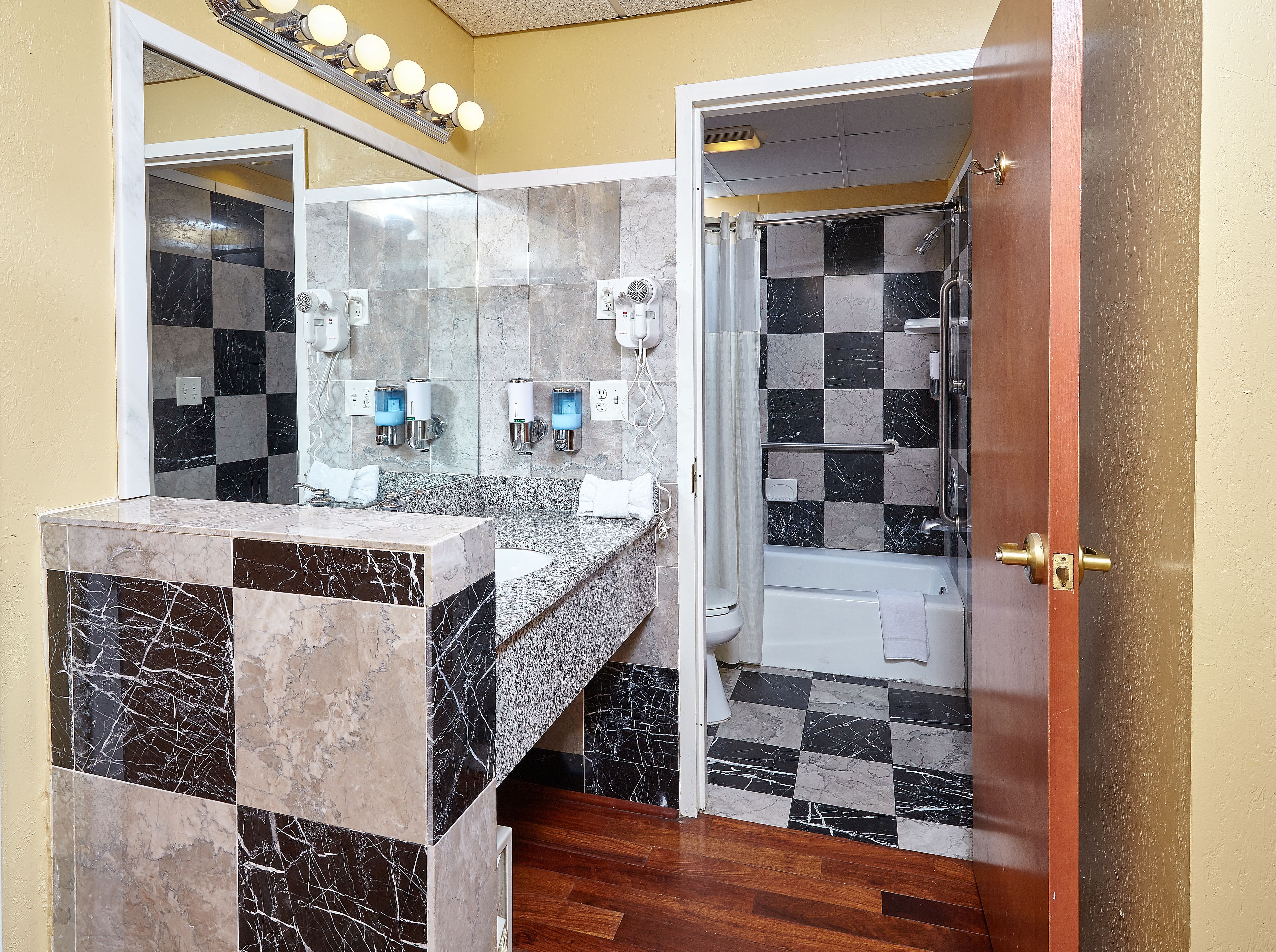 Een badkamer met een marmeren wastafel, een douche met glazen deur en een spiegel boven de wasbak.