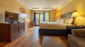 A hotel room with a bed, a desk, a television, and a window with curtains.
