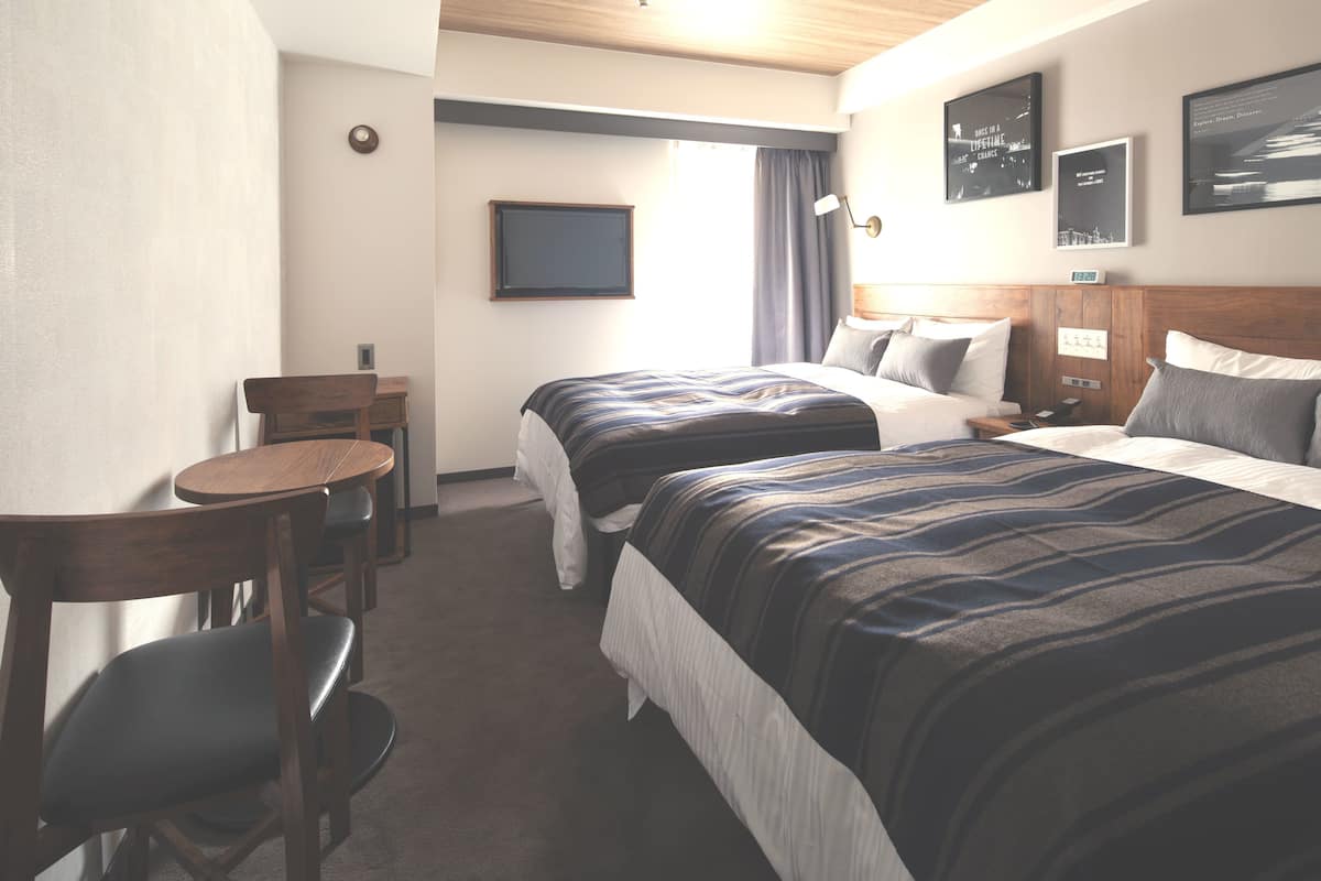 Habitación de hotel con dos camas, un escritorio y una silla.