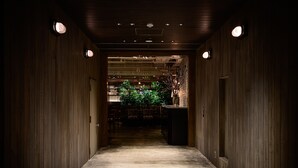A corridor with wooden walls and ceiling, leading to a seating area with tables and chairs. - Hotel The Knot Yokohama (Yokohama)