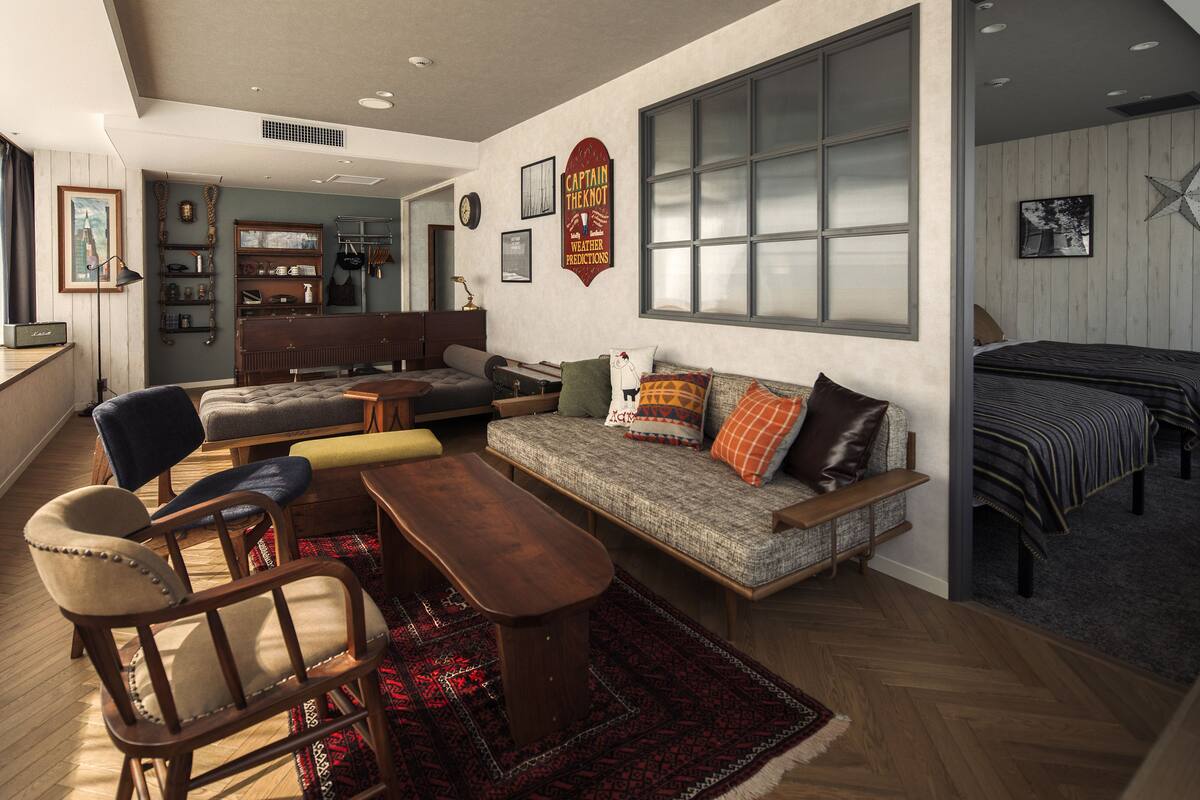 Amplia sala de estar con sofá, sillas y una mesa de centro de madera. Se observa un gran ventanal con persianas, un reloj de pared y un letrero decorativo.