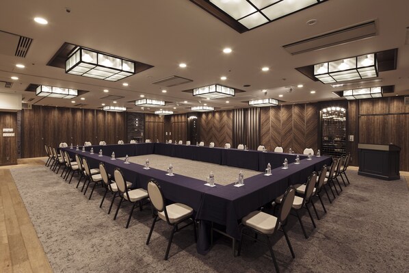 A conference room with a long table, chairs, and a podium.