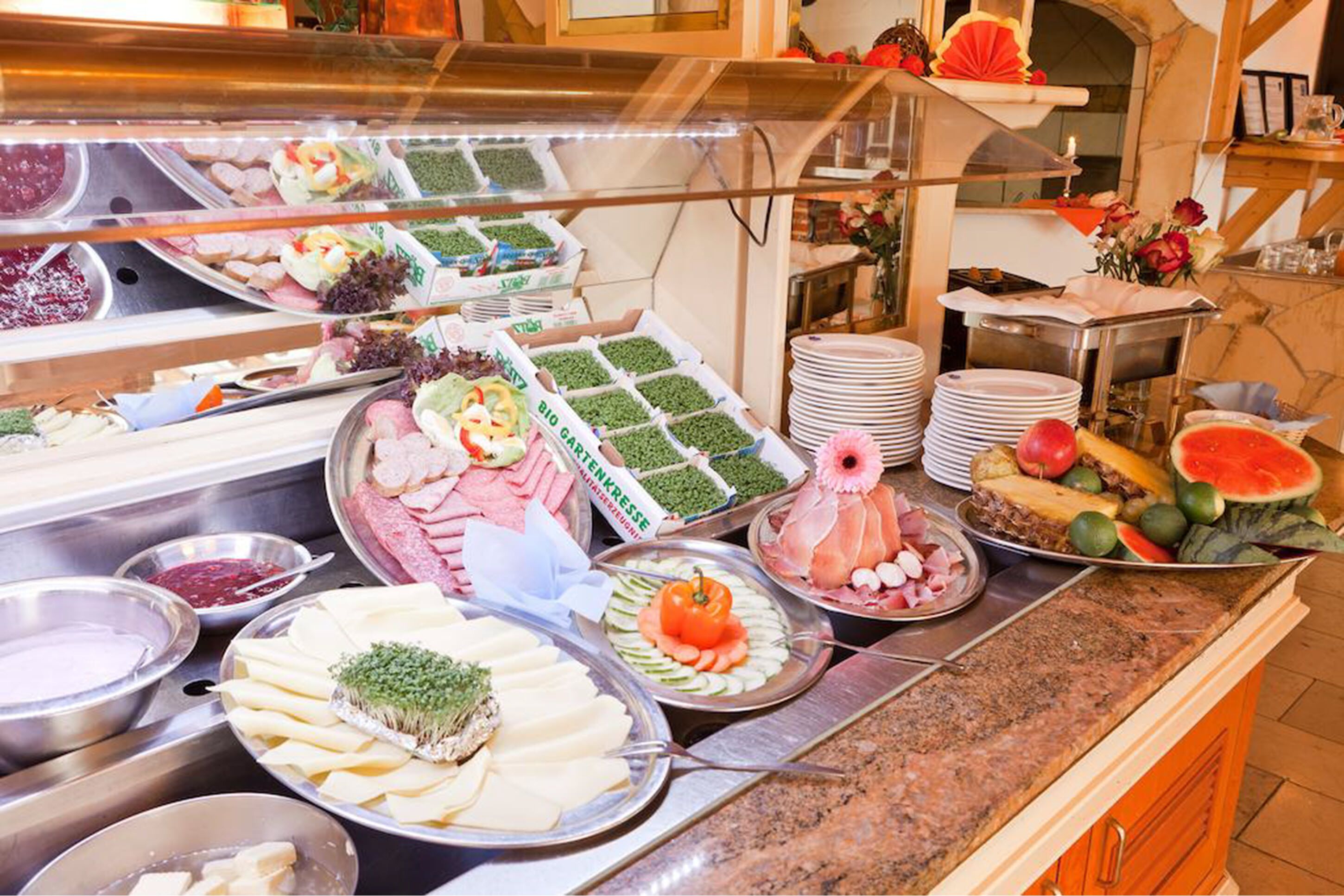 Un bufé con diversos alimentos, entre ellos carnes, quesos y verduras.
