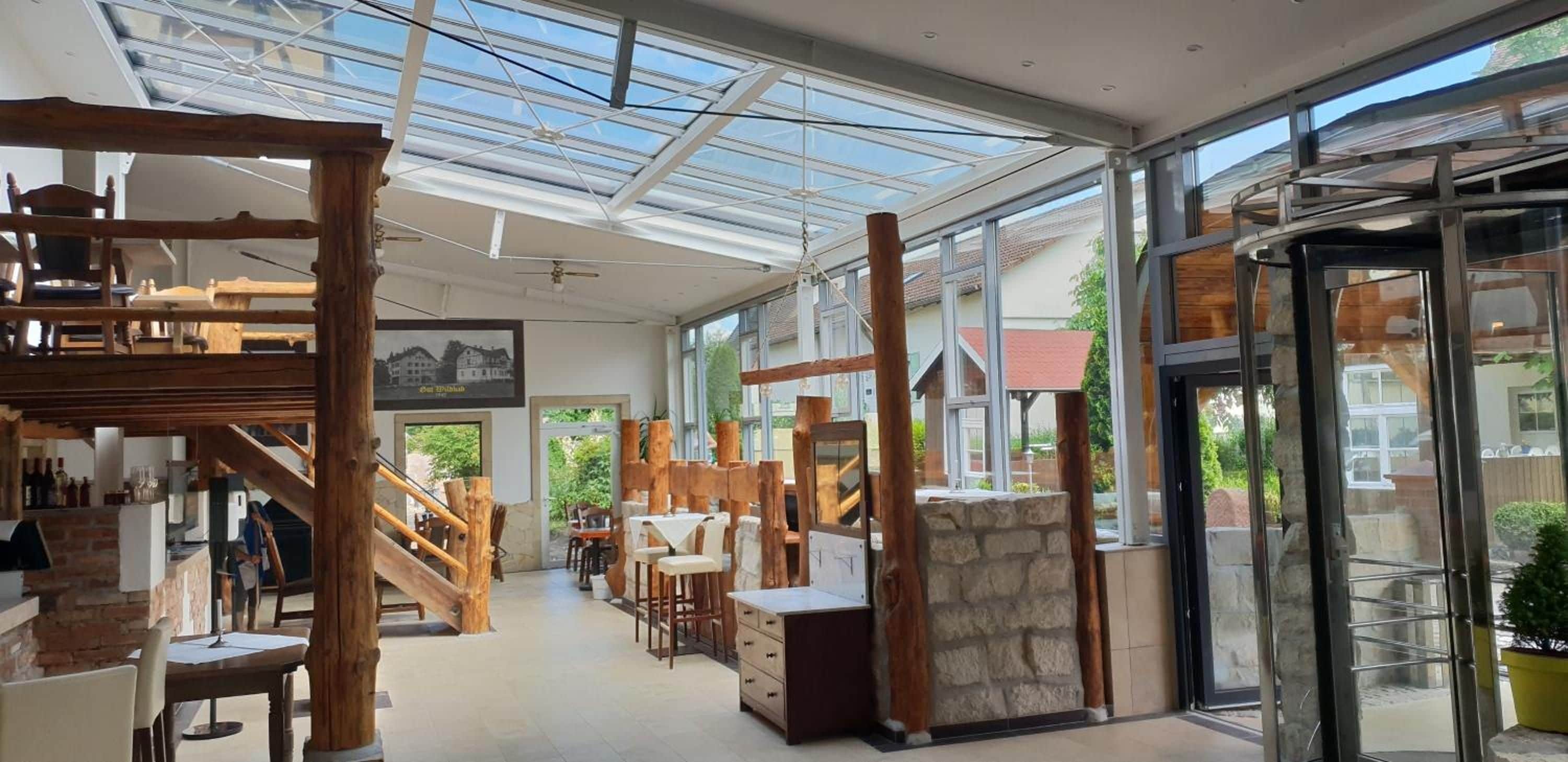 A spacious interior with a high ceiling, wooden beams, and a glass door leading outside.
