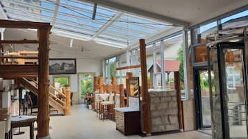 A spacious interior with a high ceiling, wooden beams, and a glass door leading outside.