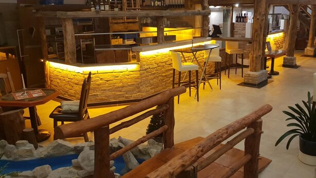 A rustic bar area with stone walls and wooden furniture, including a bar counter and seating. - Seebauer Hotel Gut Wildbad (Wemding)