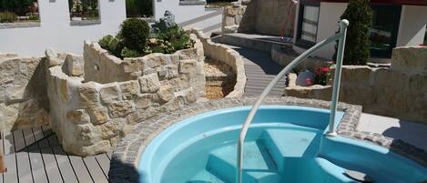 A swimming pool with stone walls and a wooden deck.