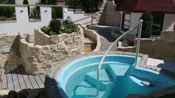 A swimming pool with stone walls and a wooden deck.