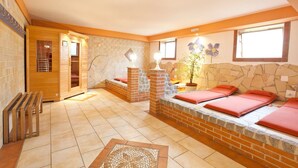 A spa room with a stone wall, wooden benches, and a small window. - Seebauer Hotel Gut Wildbad (Wemding)