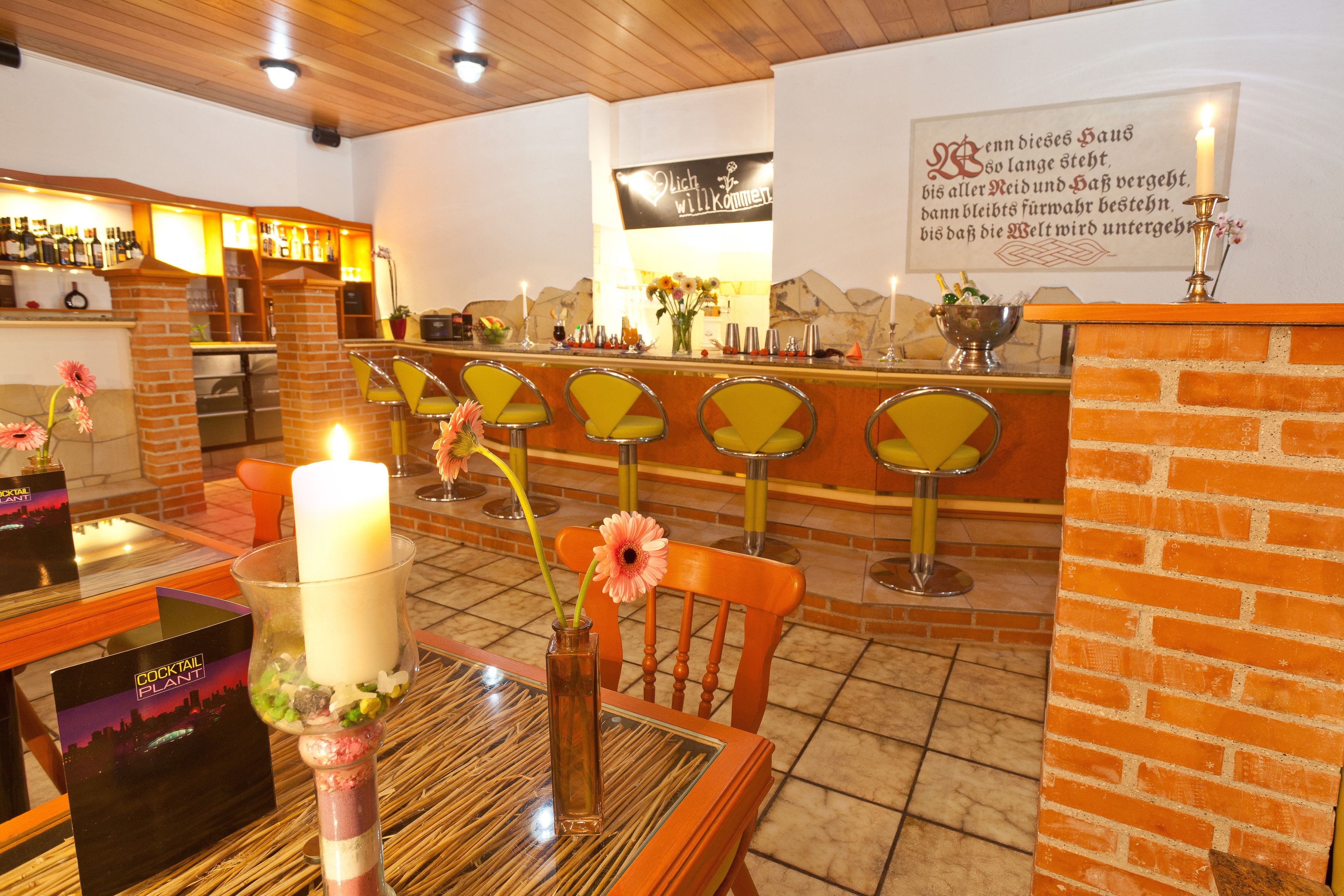 A bar area with a brick counter, multiple bar stools, and a candle centerpiece.