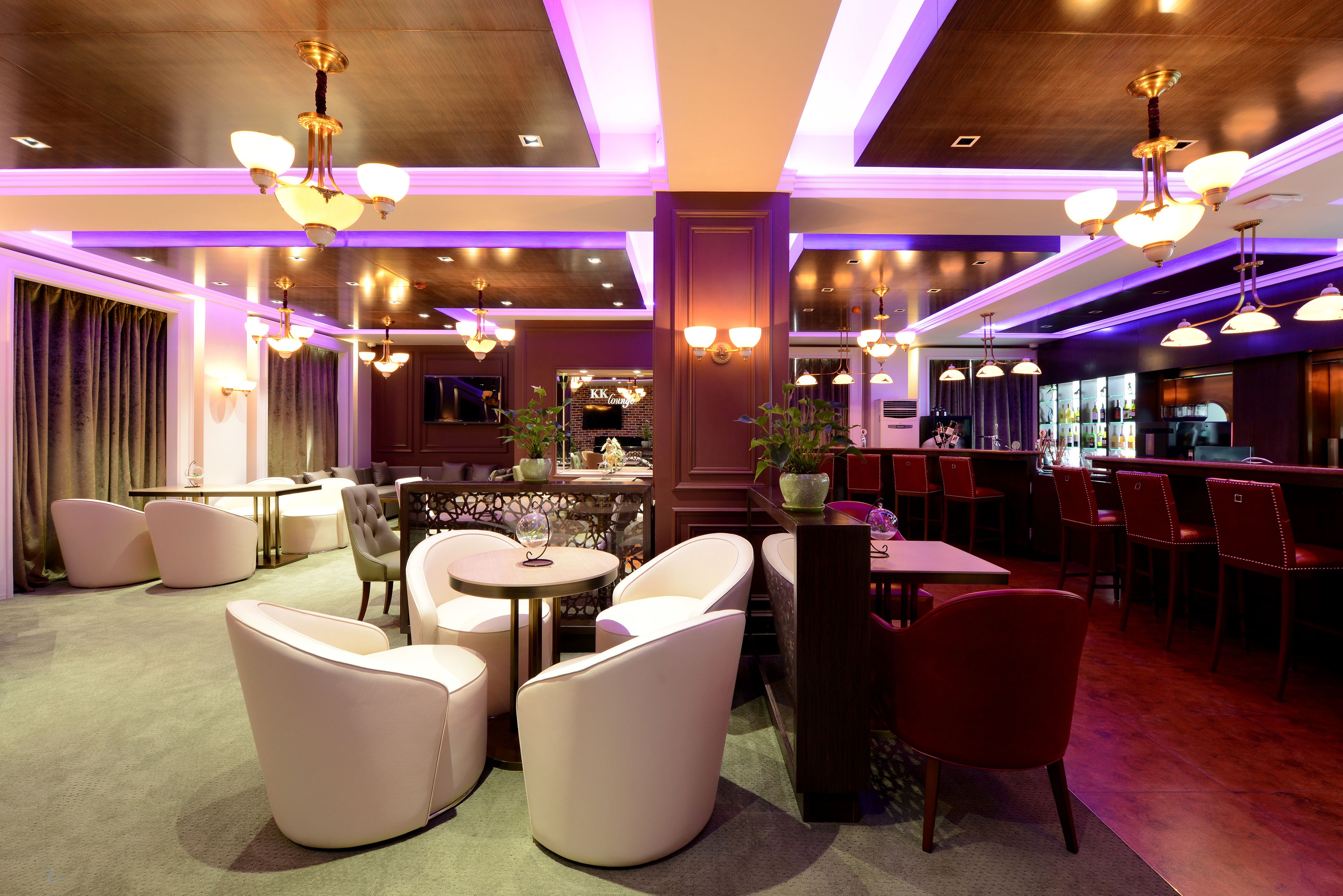 A modern interior with seating areas, a bar, and a visible restaurant named 'KK Lounge'.