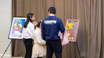 A group of people observing paintings on easels.