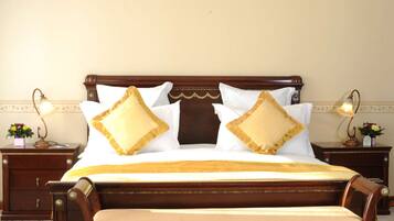 A neatly made bed with a wooden headboard, two bedside tables with lamps, and a floral arrangement on one of the tables.
