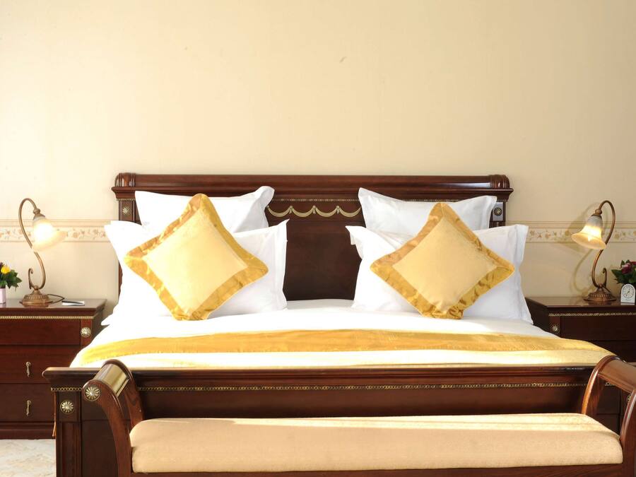 A neatly made bed with a wooden headboard, two bedside tables with lamps, and a floral arrangement on one of the tables.