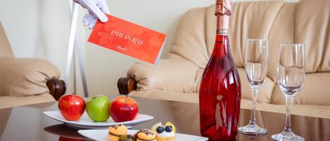 A table with a bottle of red wine, two glasses, and plates with fruits and pastries.