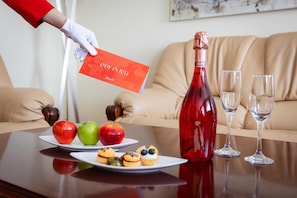 A table with a bottle of red wine, two glasses, and plates with fruits and pastries. - Kempinski Hotel Khan Palace (Ulaanbaatar)